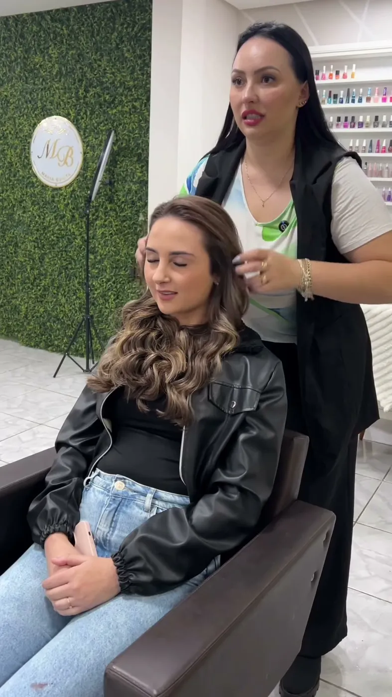 Profissional finalizando as ondas de uma cliente diante da parede verde com o espelho MB